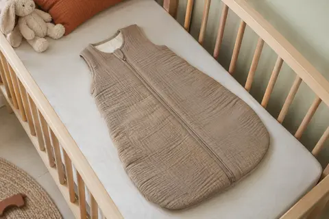 Gigoteuse bébé sans manches en bambou, avec fermeture à glissière et col arrondi, sur un lit en bois clair